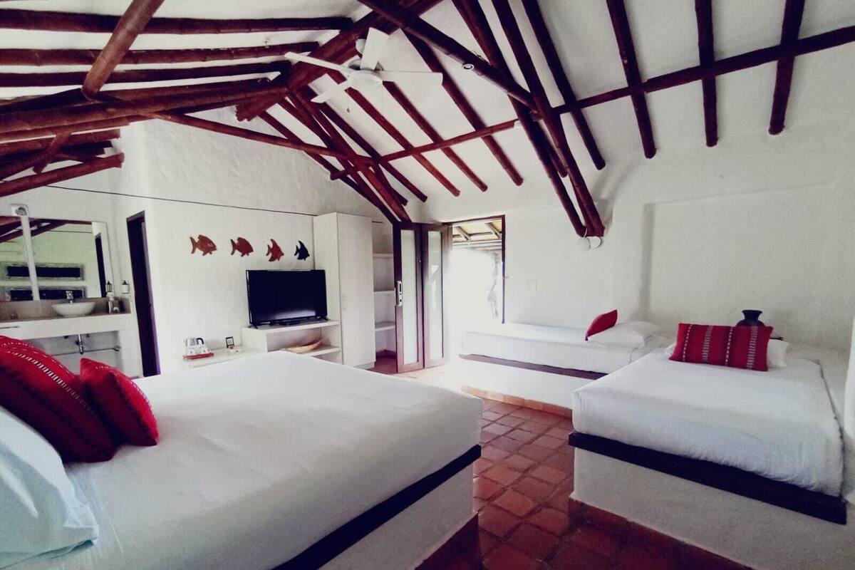 Quarto com duas camas, televisão e banheiro.