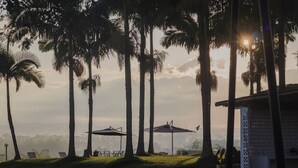A serene outdoor setting with palm trees, a gazebo, and a building with a patterned facade. - Hotel Rancho Eden (Armenia)