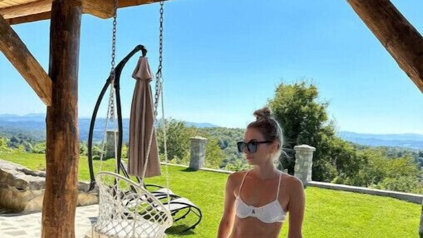 A person in a white bikini standing in a hot tub with a view of a green landscape and a clear sky. - Vineyard Chalet With Jacuzzi and Sauna for FREE (Trebnje)