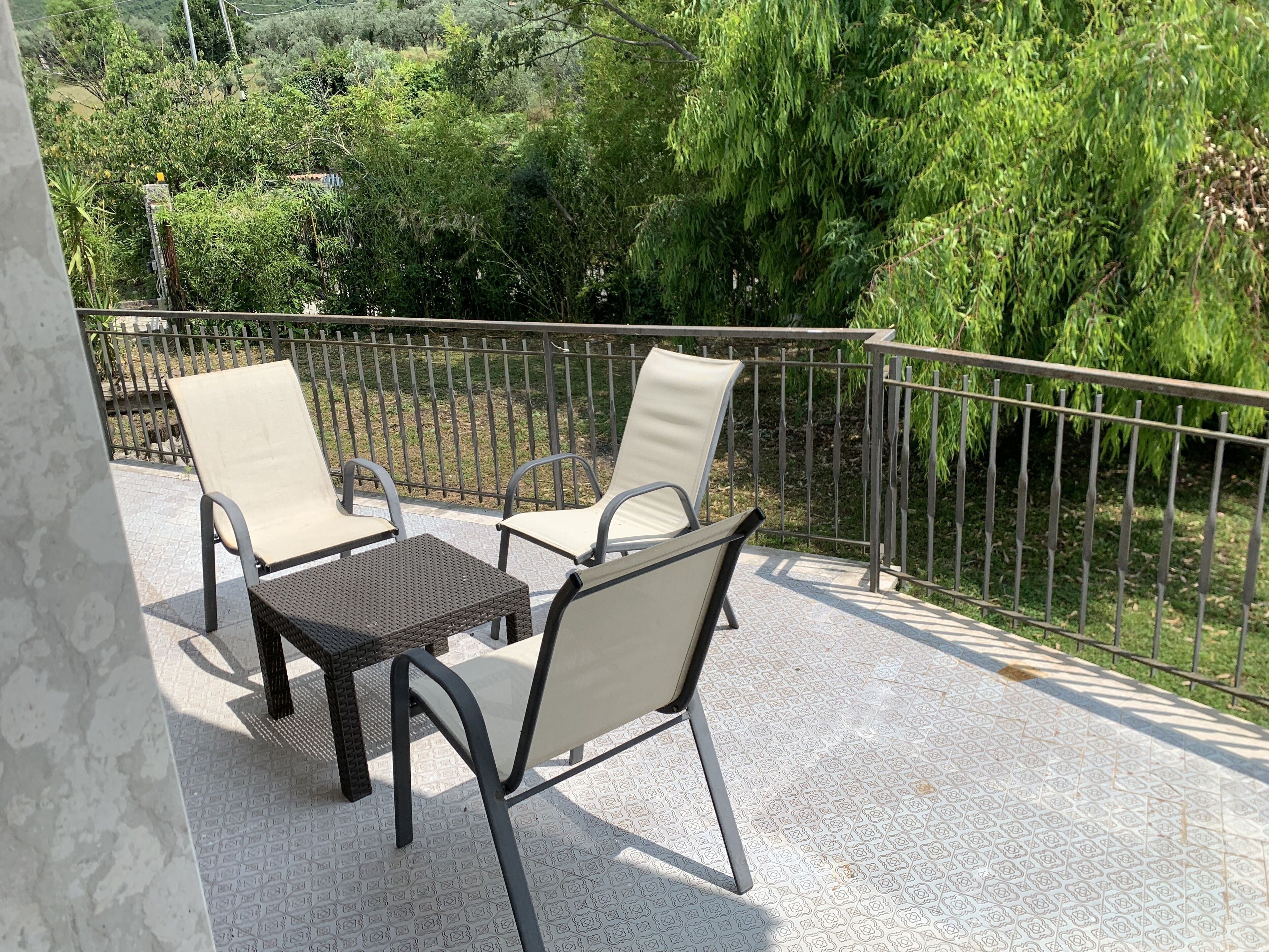 Un balcon avec deux chaises et une table, entouré d’une rambarde en métal et doté d’un sol à motifs.