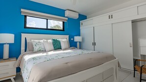 Une chambre avec un grand lit, une armoire blanche et une fenêtre équipée de stores.