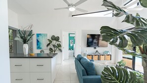Un salon moderne avec un canapé, un téléviseur et un ventilateur de plafond.