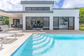 A modern house with a swimming pool, large glass doors, and a patio area. - Beautiful 3 Bedroom Villa located in the heart of Sosúa.
 (Sosúa)