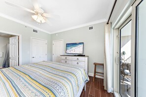 A bedroom with a bed, a television, a ceiling fan, and a sliding glass door to a balcony. - Crystal  Tower   404 (Gulf Shores)
