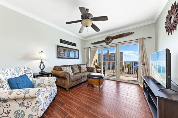 A living room with a ceiling fan, a sofa, a coffee table, and a television. - Crystal  Tower   404 (Gulf Shores)