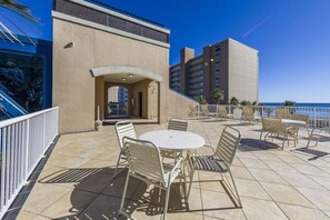 An outdoor patio with a round table and chairs, a covered entrance, and a view of the ocean. - Crystal  Tower   404 (Gulf Shores)