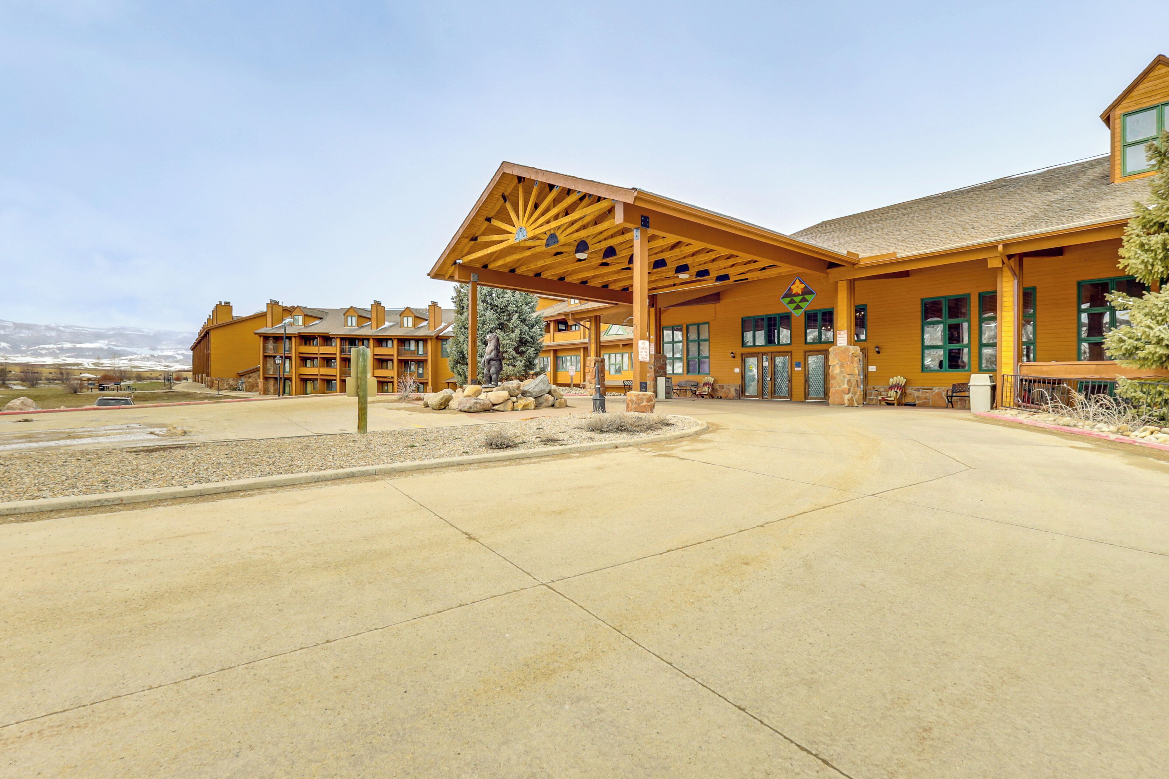 A lodge with a covered patio, stone seating, and a mountain backdrop.