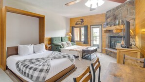 A cozy room with a bed, a green sofa, a dining table, and a fireplace.