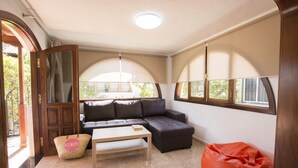 A living room with a sofa, a coffee table, a red bean bag, and a wicker basket.