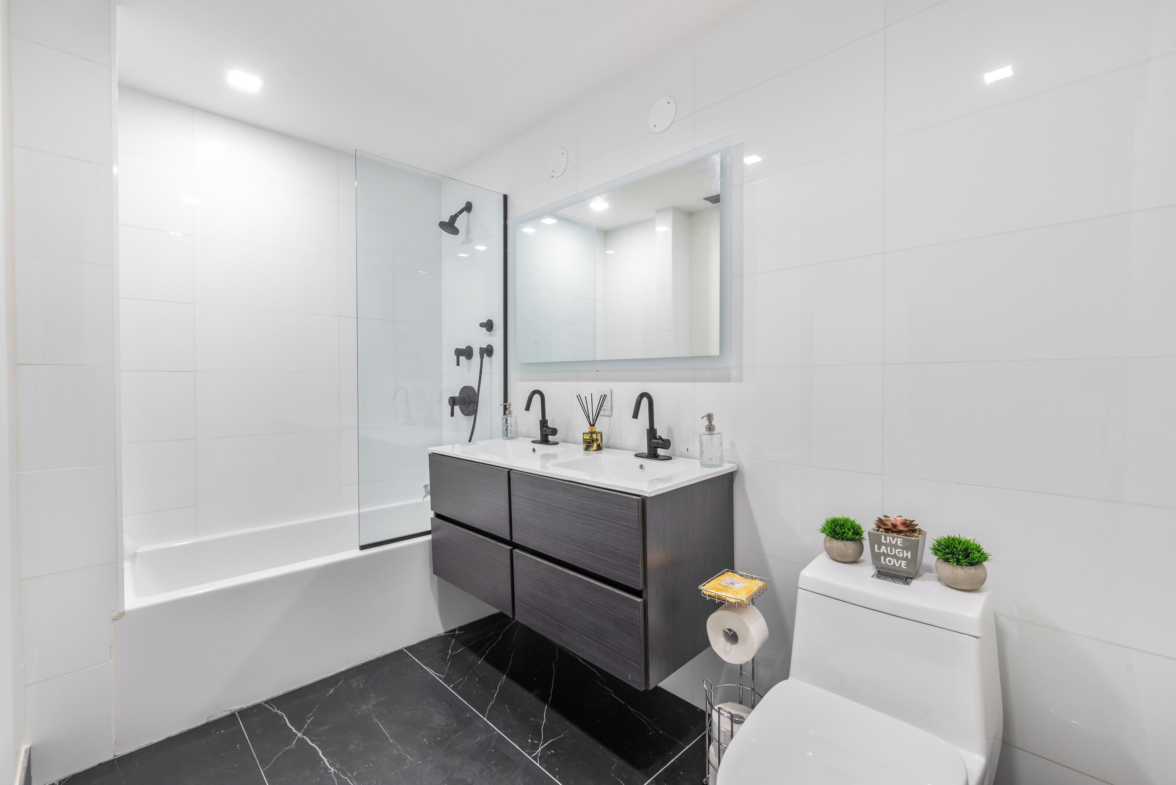 Ein modernes Badezimmer mit einer Badewanne, einer Toilette und einem Waschtisch mit Spiegel.
