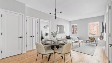 A modern dining area with a round table, chairs, and a chandelier.