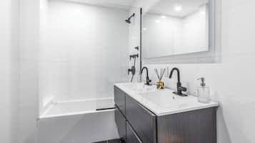 A modern bathroom with a white vanity, black marble floor, and a large mirror above the sink.