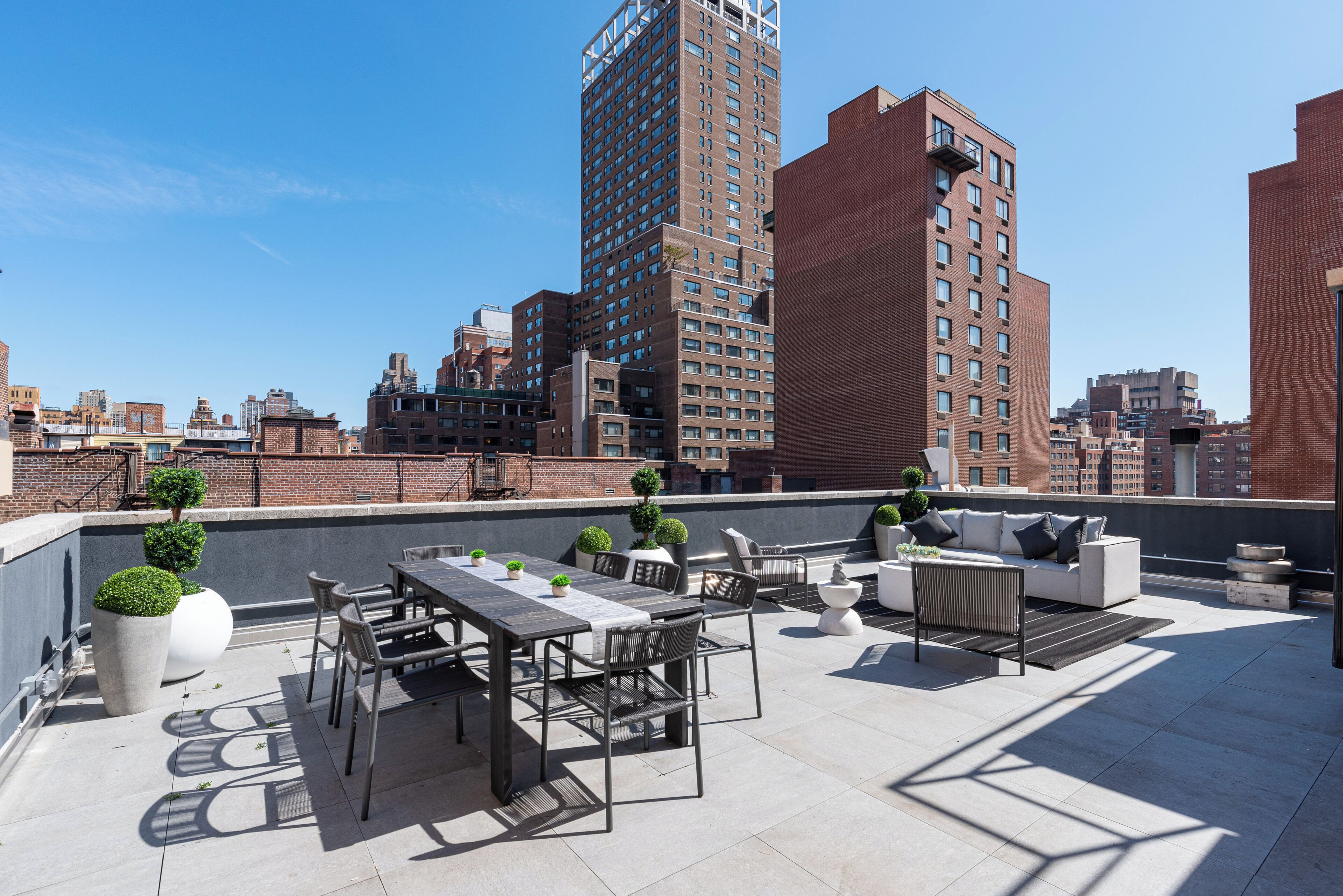 Terraço no telhado com área de refeições, assentos e plantas em vasos.