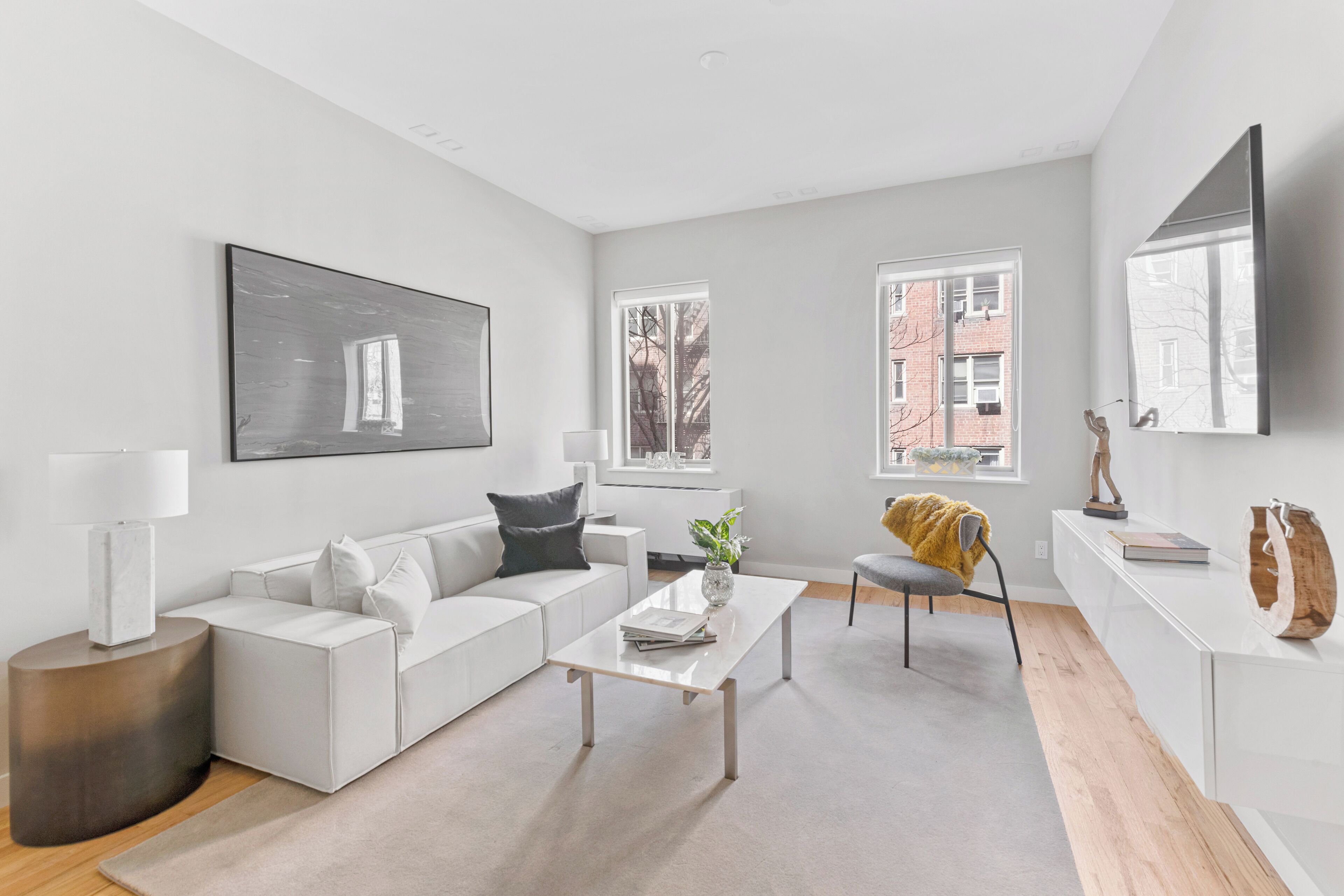 Un salon moderne avec un canapé blanc, une table basse et un téléviseur fixé au mur.