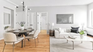 A modern living room with a dining area, white furniture, and a large abstract painting on the wall. - The Sixty Two (New York)