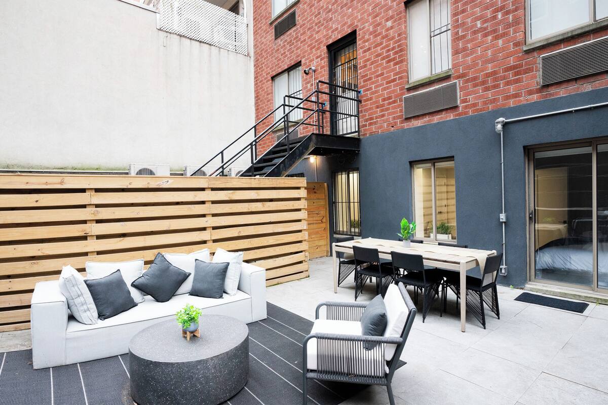 A patio with a white sofa, round coffee table, and wicker chairs.
