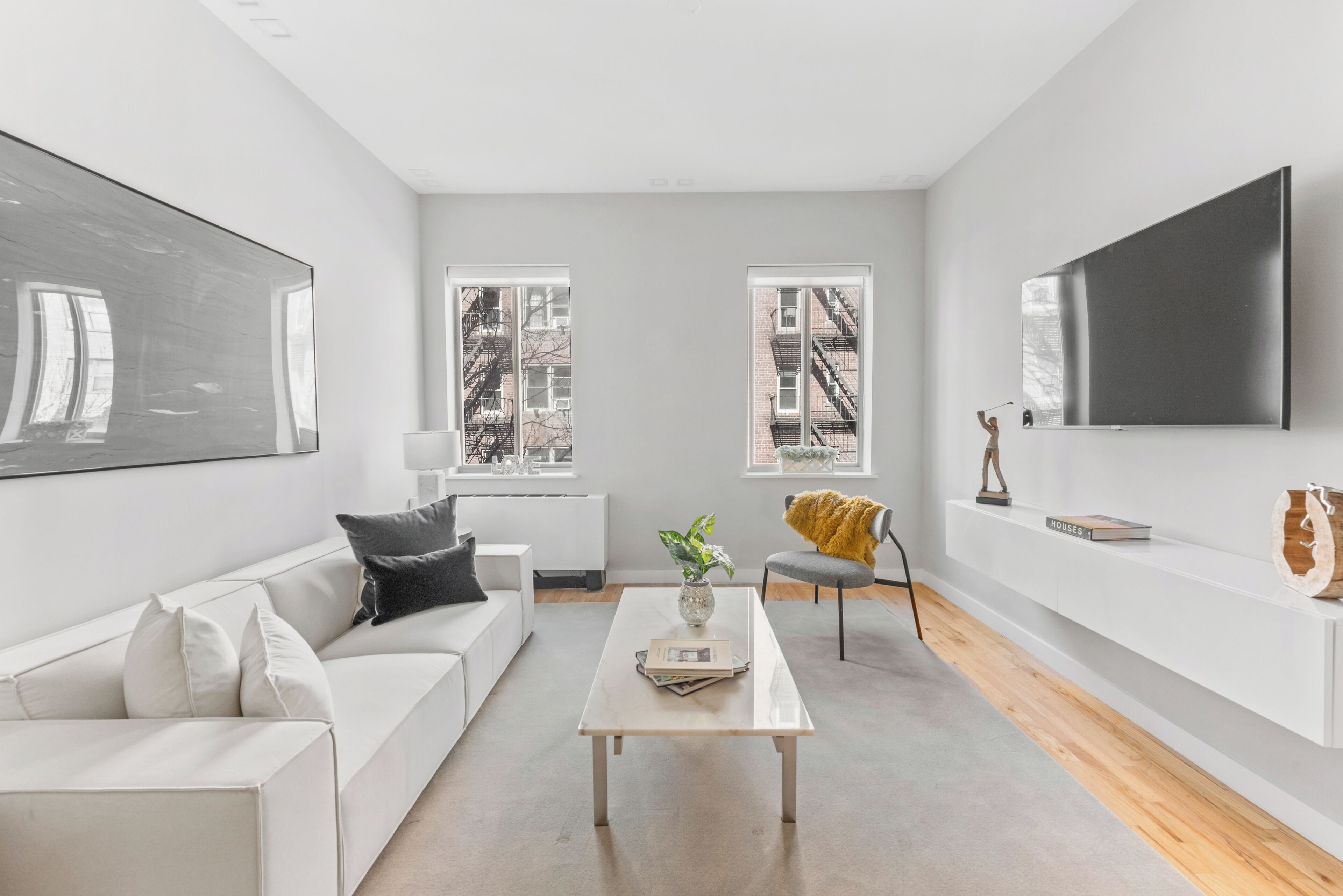 Un salon moderne avec un canapé blanc, une table basse et un téléviseur fixé au mur.