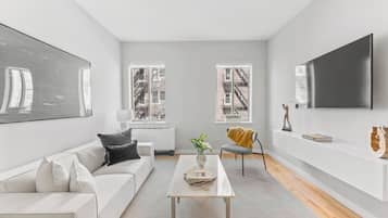 Un salon moderne avec un canapé blanc, une table basse et un téléviseur fixé au mur.