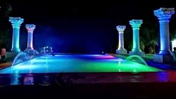 A nighttime view of a fountain with illuminated columns and a water feature.