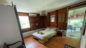 Una habitación con cama, una silla, una mesita, una lámpara colgante y vistas al exterior.