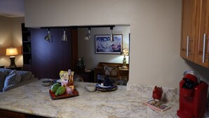 Ett kök med en bänkskiva i marmor, en kaffebryggare och en liten staty.