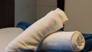 Een bed met blauw beddengoed en twee opgerolde witte handdoeken.