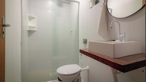 Een moderne badkamer met een douchecabine van glas, een wit toilet en een houten wastafelmeubel met een wastafel.