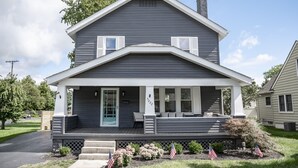 A two-story house with a front porch, a chimney, and a mailbox. - 3 BR cozy + renovated walkable downtown stay (Hilliard)