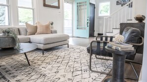 A modern living room with a sectional sofa, a coffee table, and a patterned rug. - 3 BR cozy + renovated walkable downtown stay (Hilliard)