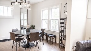 A modern dining area with a round table, six chairs, and a chandelier. - 3 BR cozy + renovated walkable downtown stay (Hilliard)