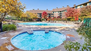 A hotel pool area with a hot tub, lounge chairs, and a building in the background. - Heated Pool Hot Tubs Sauna Gym Mtn Views Appalachian @ Mtn Creek #225 (Vernon)
