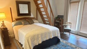 Une chambre à coucher avec un lit, une échelle en bois, une chaise et une fenêtre avec des stores.