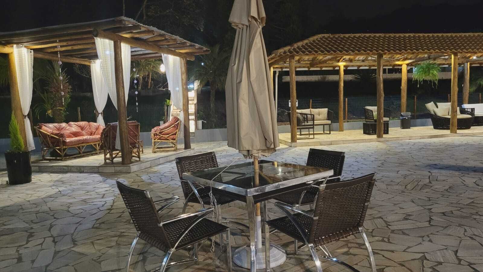 An outdoor patio area with a stone floor, a round table with chairs, and a covered seating area with wicker furniture.
