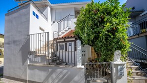 Ein Gebäude mit weißer Fassade, einem Metallgitter und einer Treppe, die zu einem Balkon führt.