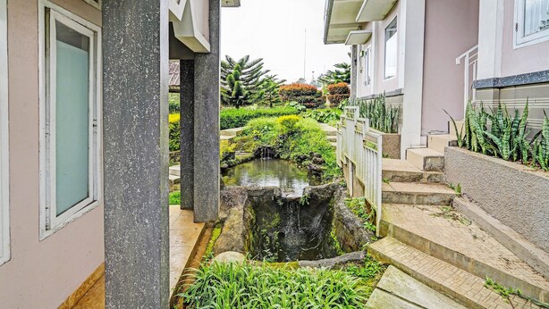 A narrow alleyway with a small water feature, steps, and greenery. - OYO 92023 Singgasana Cipelah Syariah (Tjikadjang)