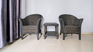 Two wicker chairs and a small side table in a room with a tiled floor and a plain wall. - OYO 92023 Singgasana Cipelah Syariah (Tjikadjang)