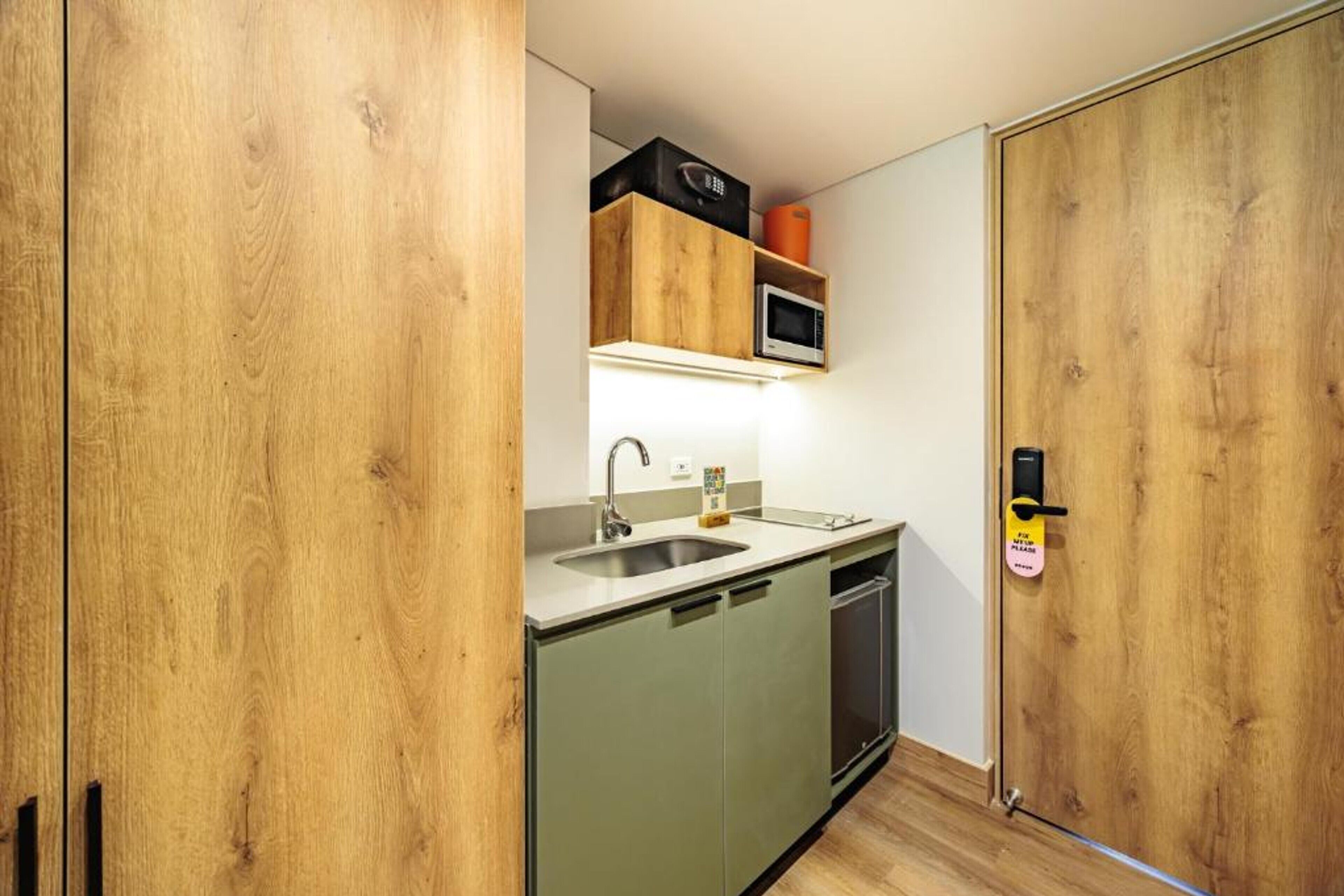 A compact kitchen with a sink, microwave, and cabinets.