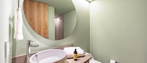 A bathroom with a round mirror, a sink, and a toilet.