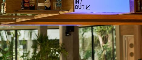 A bar area with a check-in/out sign, bottles of liquor, and a coffee machine.
