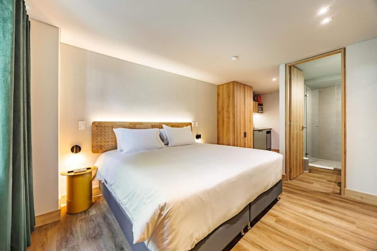 A modern bedroom with a large bed, wooden headboard, and a walk-in closet.