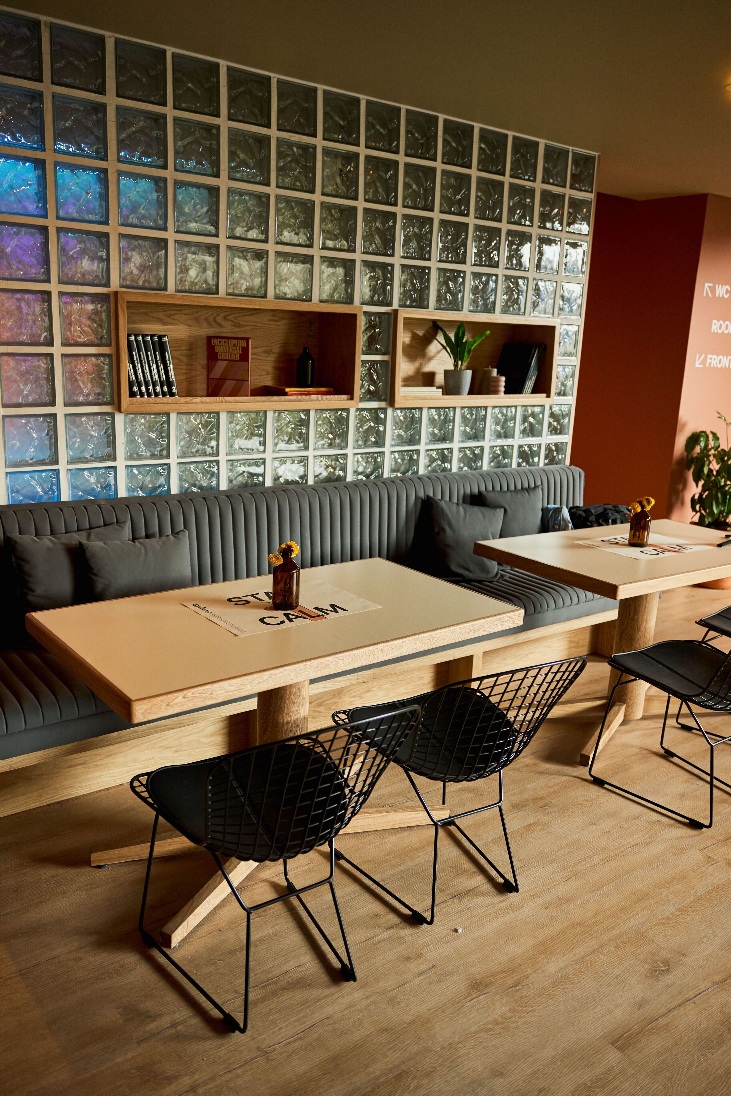 A modern interior with a sofa, tables, and chairs. There are shelves with decorative items and a wall with a mosaic pattern.
