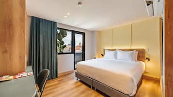 Una habitación de hotel moderna con una cama grande, un escritorio y vistas a la ciudad a través de la ventana.