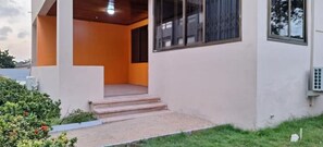 Stroll up to the covered entrance, surrounded by lush greenery.