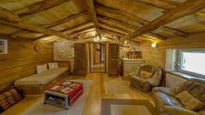 A cozy log cabin interior with a loft bedroom, a sofa, a leather armchair, and a fireplace. - Gîte L'Échappée en Vercors (Choranche)