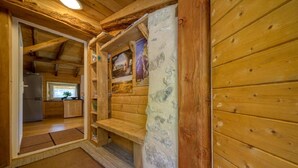 A wooden interior with a kitchen area, a built-in bench, and a wall with a poster. - Gîte L'Échappée en Vercors (Choranche)