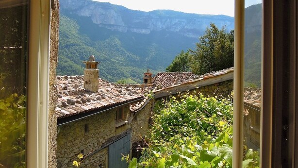 A rustic stone building with a tiled roof and a chimney, overlooking a mountainous landscape. - Gîte L'Échappée en Vercors (Choranche)