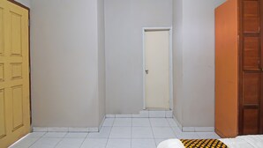 Een kamer met een betegelde vloer, een gesloten deur en een airconditioningunit aan de muur.