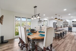 A spacious kitchen with a dining area, featuring a large window, modern appliances, and a central island.