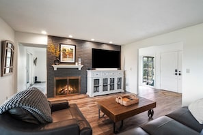 A modern living room with a fireplace, a television, and a cozy seating area. - The Lodge at Shaw Ranch | Hocking Hills, 30 Acres (Rockbridge)