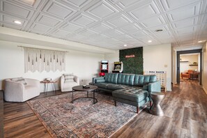 A modern living room with a sectional sofa, a coffee table, and a macrame wall hanging. - The Lodge at Shaw Ranch | Hocking Hills, 30 Acres (Rockbridge)